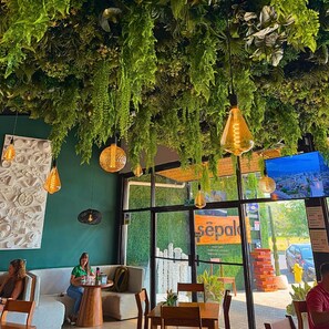 A restaurant with hanging plants, pendant lights, and a green wall. - Viva Jaco 0404 Luxury Apartment (Jacó)