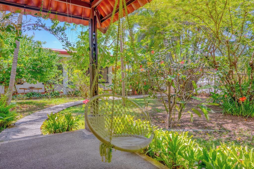 A garden with a swing chair, a pathway, and a building in the background.