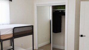 Ein Schlafzimmer mit einem Etagenbett, einem Schrank mit Schiebereflektor und einer weißen Tür.