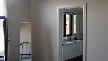 Ein Schlafzimmer mit einem Einzelbett, einem Nachttisch, einem Spiegel und einem Fenster mit Vorhängen.
