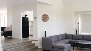Ein modernes Wohnzimmer mit einem grauen Ecksofa, einem Couchtisch und einer Treppe, die zu einer weiteren Ebene führt.