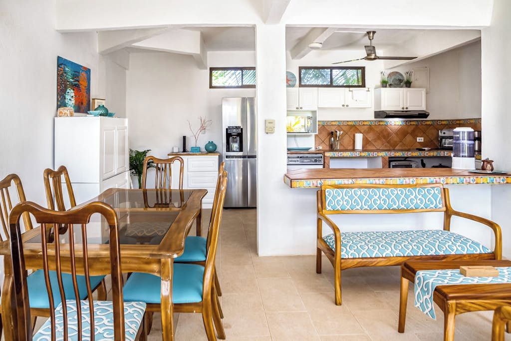 Une cuisine spacieuse avec un coin repas, comprenant un îlot central, des chaises en bois et un réfrigérateur.