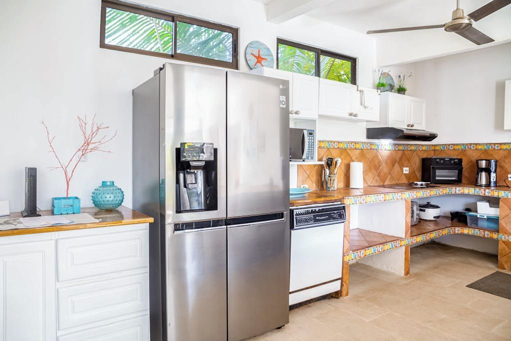 Cocina con refrigerador, microondas y estufa. Hay una ventana con vista a la vegetación.