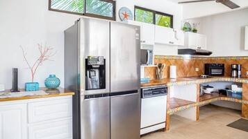 Cocina con refrigerador, microondas y estufa. Hay una ventana con vista a la vegetación.