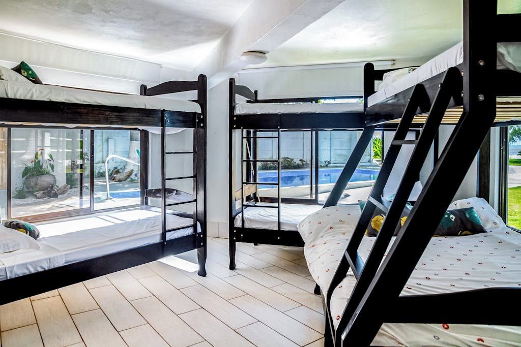 Una habitación con literas, ventanas amplias y vista a una piscina.