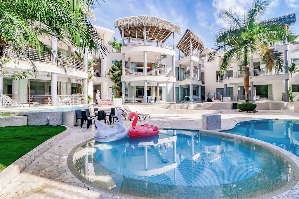 Ein Hotel mit Pool, Liegestühlen und einer Palme.
