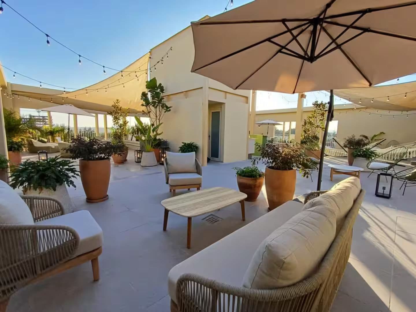 An outdoor patio area with wicker furniture, potted plants, and string lights.