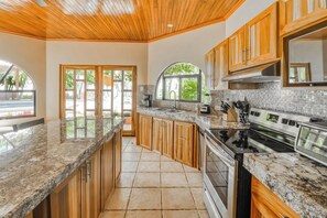 Una cocina con armarios de madera, encimera de granito, estufa y lavavajillas.