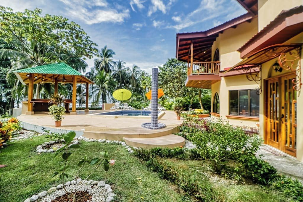 A tropical resort with a pool, a gazebo, and lush greenery.