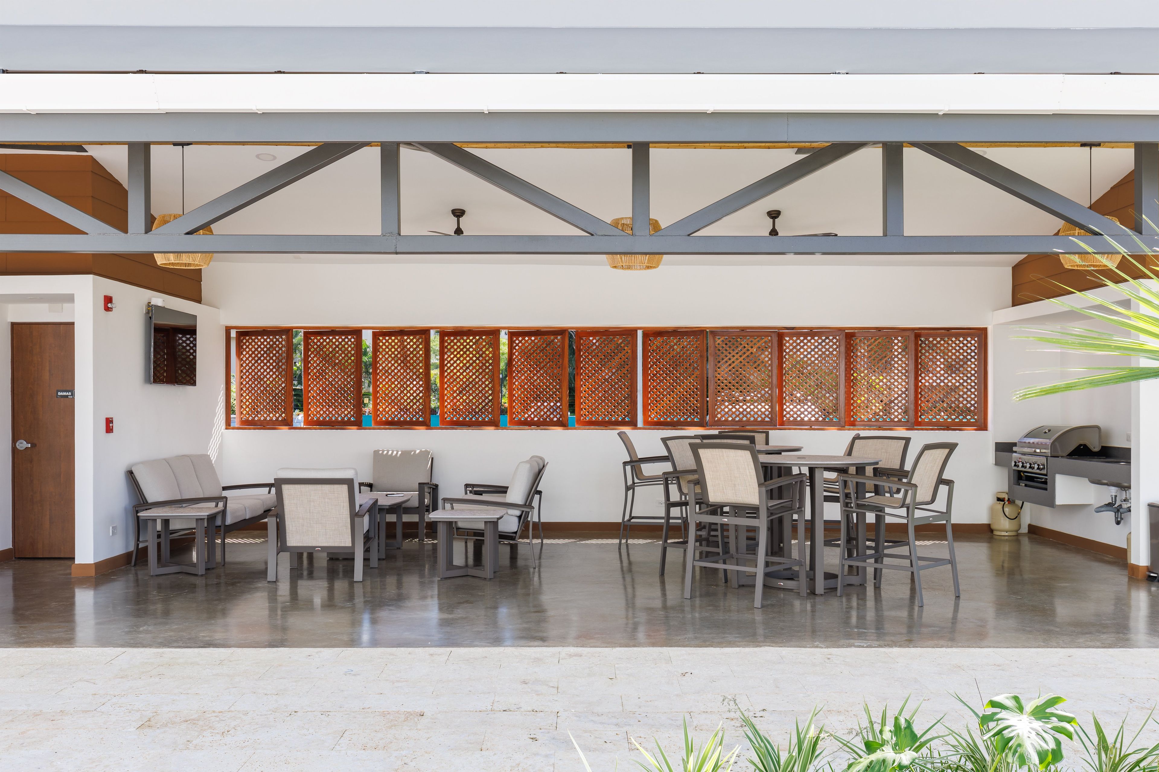 Um espaço interno amplo, com teto alto, fileira de divisórias de madeira e estação de churrasco.