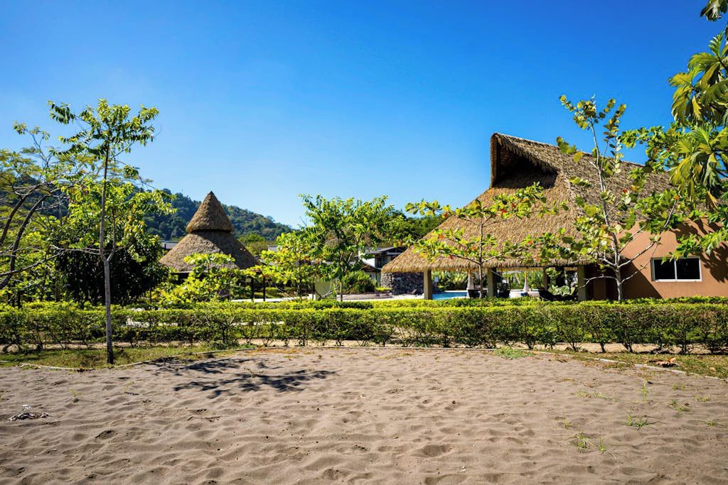 A beachside resort with thatched-roof huts and a clear blue sky.
