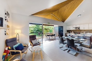 A modern interior with a dining area, kitchen, and a view of the outdoors. - Ciudad del Mar 104 Jaco Beach House with Garden View (Jaco)