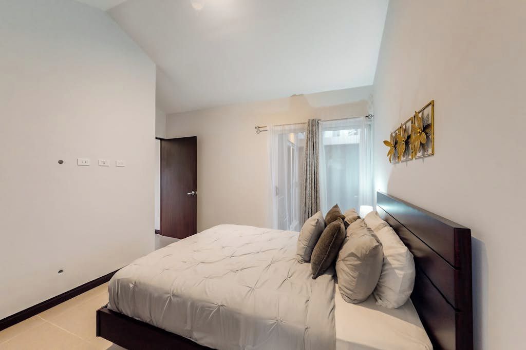 Een slaapkamer met een bed, een deur en een raam met gordijnen.