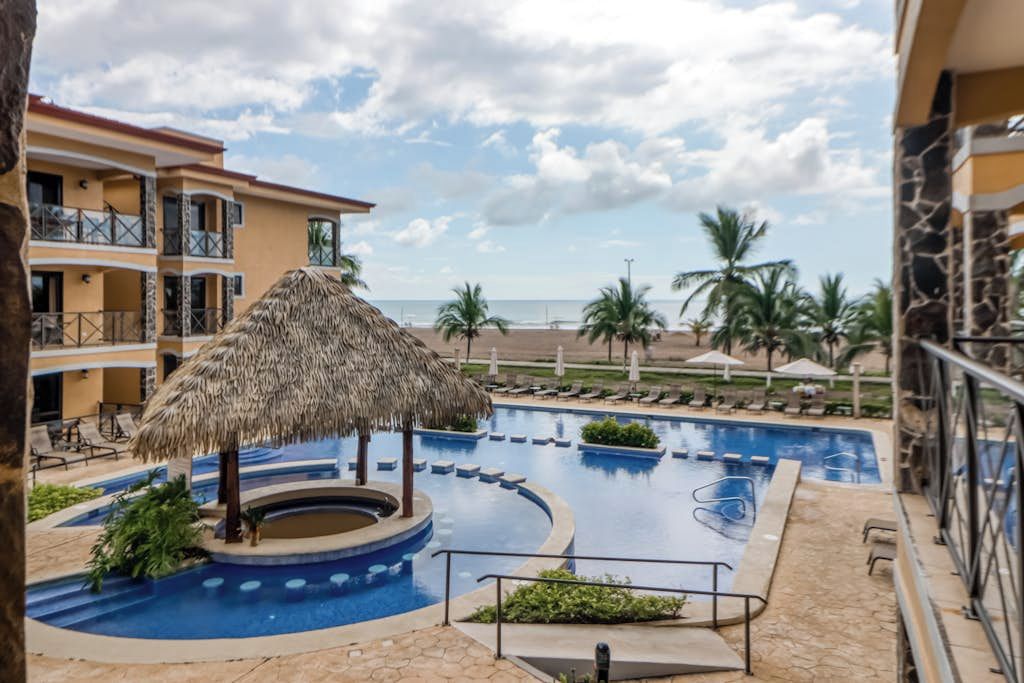 A hotel pool area with a hot tub, lounge chairs, and a view of the beach.