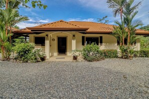 A house with a tiled roof, a front door, and a gravel driveway.
