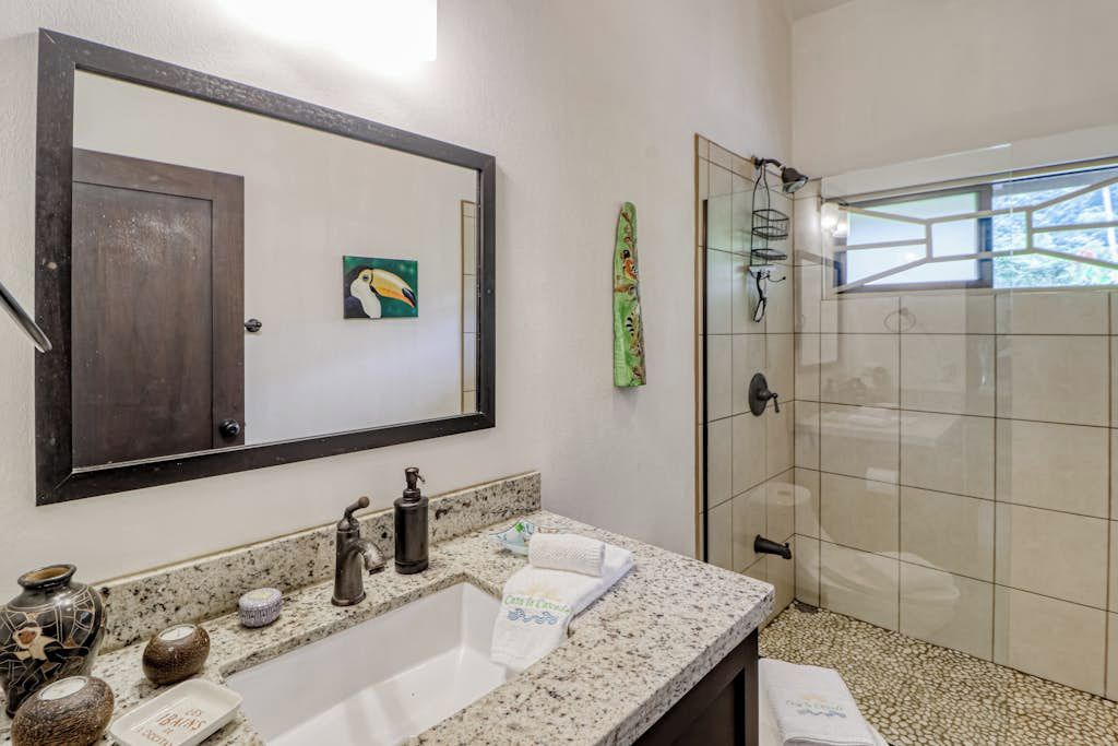 Une salle de bain avec un grand miroir, un lavabo, une douche et des objets décoratifs disposés sur le comptoir.