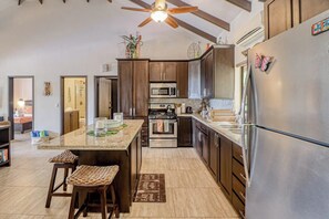 A modern kitchen with a central island, stainless steel appliances, and wooden cabinetry.