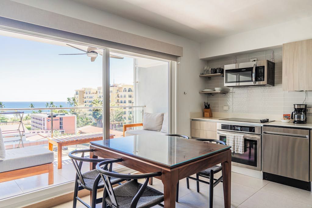Una cocina moderna con comedor, ventanas amplias y vista al mar.