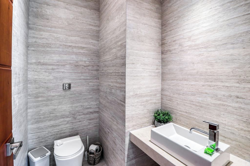 A bathroom with a white toilet, a trash bin, and a sink with a modern faucet.