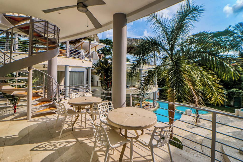 Eine Dachterrasse mit Pool, Palmen und einer Wendeltreppe.