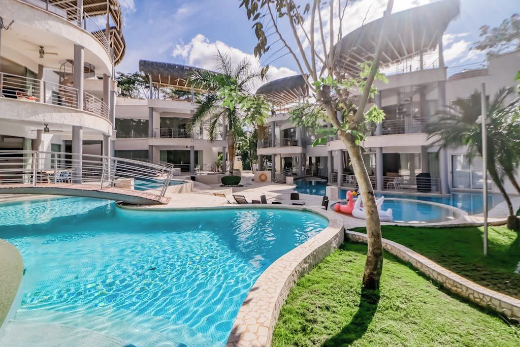 A pool area with multiple swimming pools, lounge chairs, and a covered seating area.
