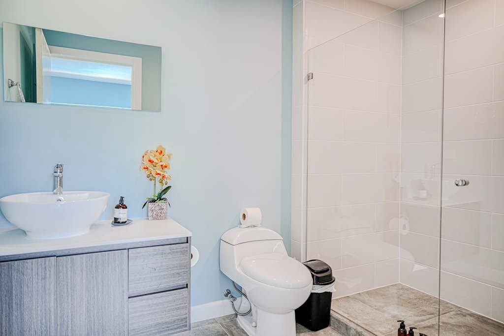 A bathroom with a white sink, toilet, and a shower area.