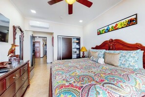A bedroom with a large bed, a ceiling fan, a wardrobe, and a painting on the wall. - The Palms 603 Oceanfront 2BR Condo in Jaco Beach (Jaco)