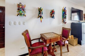 Un comedor con una mesa y sillas de madera, máscaras decorativas en la pared y un televisor.