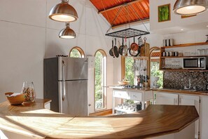 Une cuisine équipée d’un réfrigérateur en acier inoxydable, d’un plan de travail en bois, de casseroles suspendues et d’un four à micro-ondes.