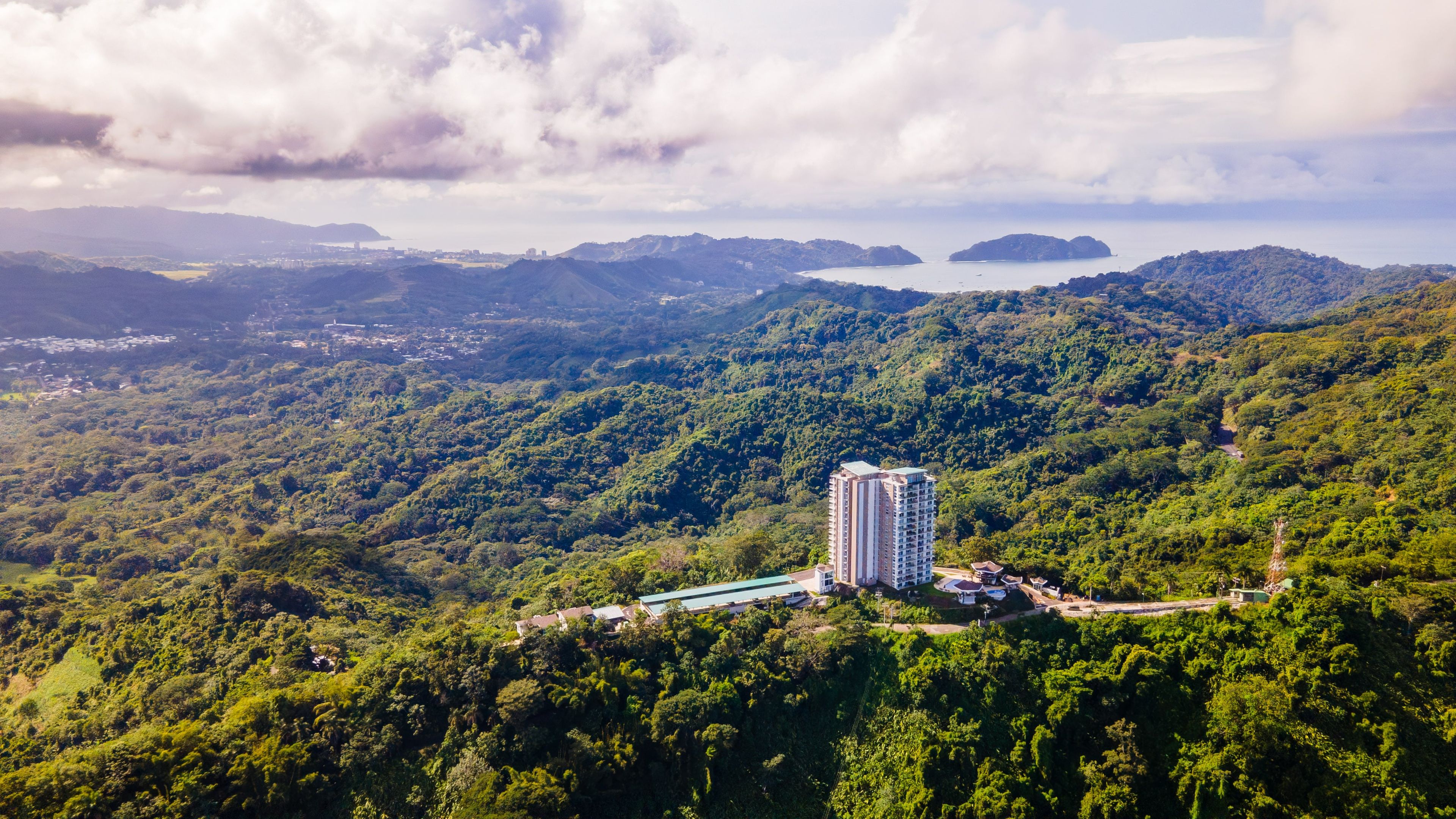 Un edificio moderno e slanciato, immerso in dolci colline verdi e con vista sul mare.