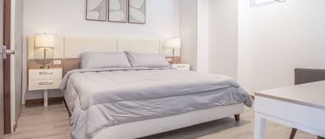 A modern bedroom with a bed, bedside tables, and a desk.