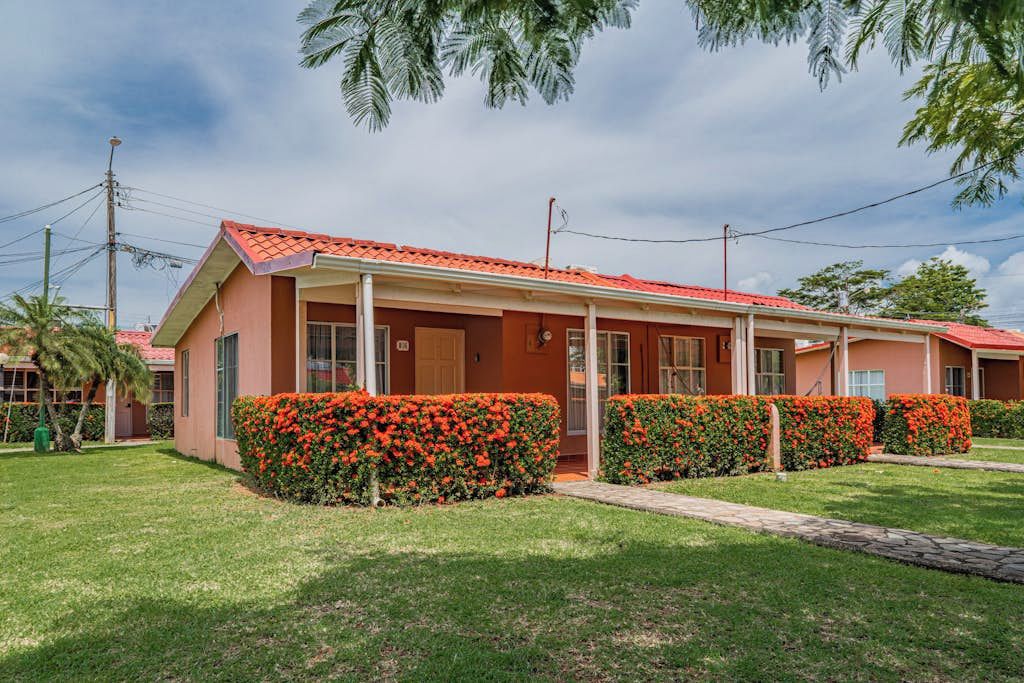 Ein zweistöckiges Motel mit rotem Dach, überdachter Veranda und gepflegten Hecken.
