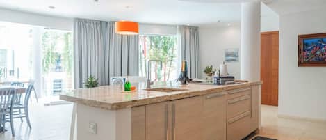 A modern kitchen with a central island, a dining area with chairs, and a view of the outdoors.