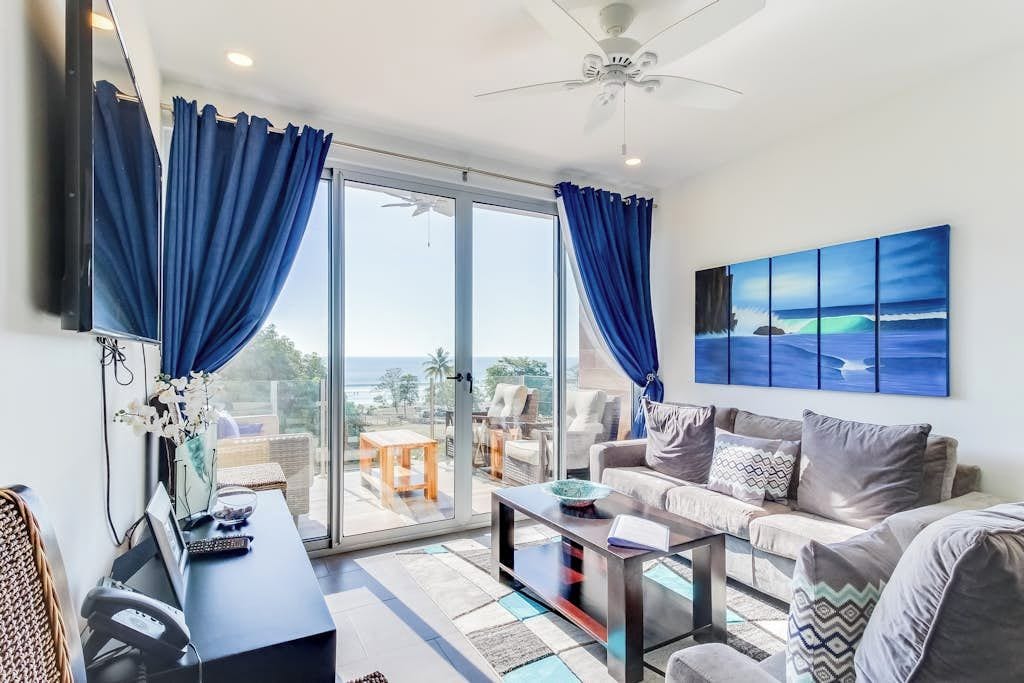 A modern living room with a sofa, coffee table, and a painting of the ocean.