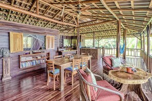 A wooden interior with a dining area, seating, and a ceiling fan. - Casa Verde Beachfront Home in Cabo Matapalo (Cabo Matapalo)