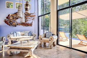 A spacious room with a large window, a unique wall art piece, and a seating area with patterned furniture. - Villa Celeste Luxury Villa with Private Pool (Manuel Antonio)