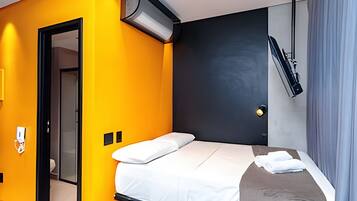 Une chambre d’hôtel avec un lit, une porte et un climatiseur fixé au mur.