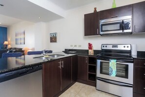 A modern kitchen with dark wood cabinets, stainless steel appliances, and a dishwasher. - The Palms 703 Oceanfront 2BR Condo in Jaco with Resort Pool (Jaco)