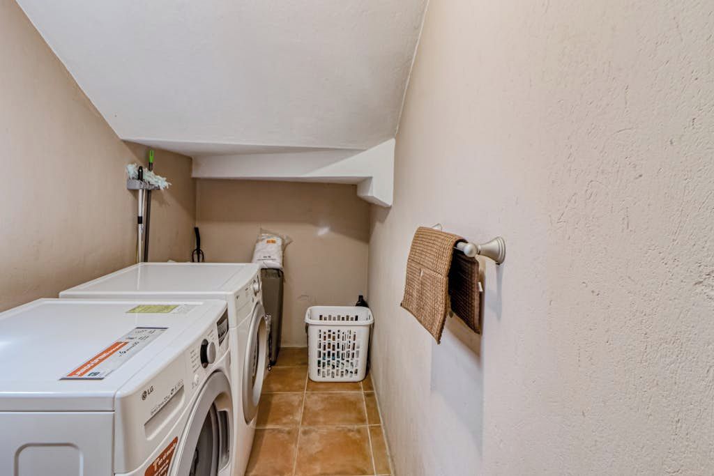 Un cuarto de lavado con lavadora, secadora y una cesta.