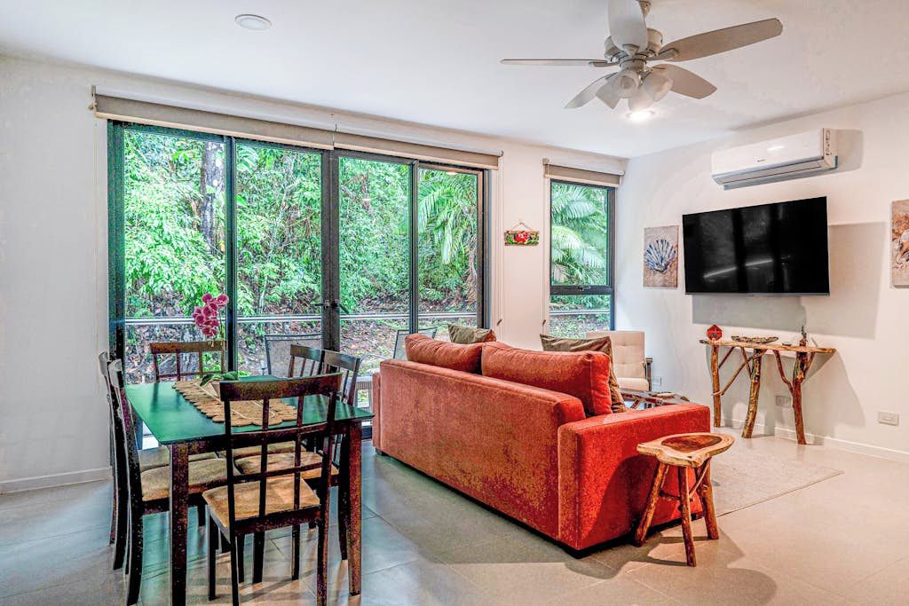 A living room with a sofa, TV, and dining area with chairs and a table.