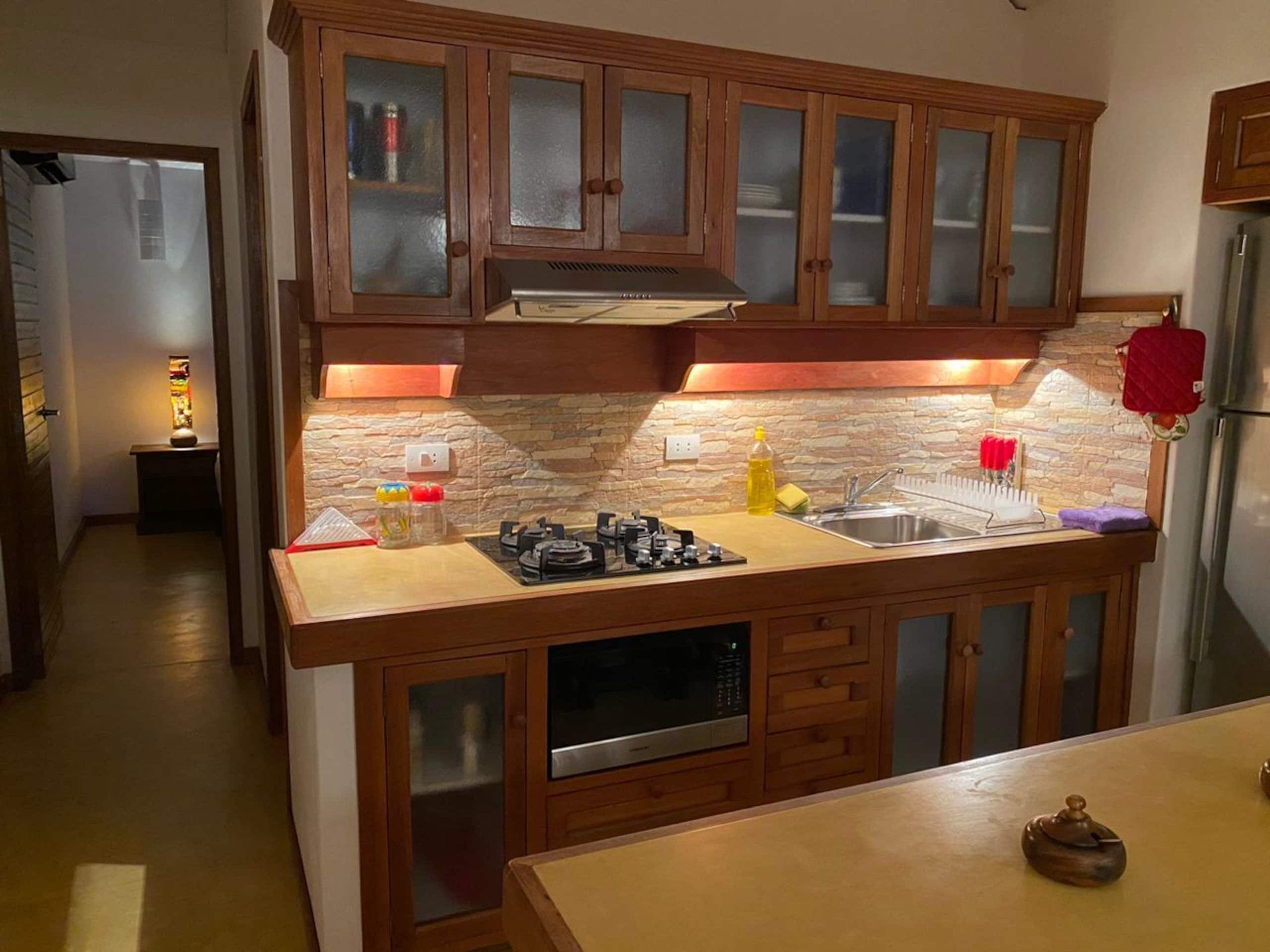 A kitchen with wooden cabinets, a built-in oven, and a stainless steel sink.