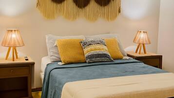 Una camera da letto con un letto, due comodini, una decorazione in macramè a parete e due applique.