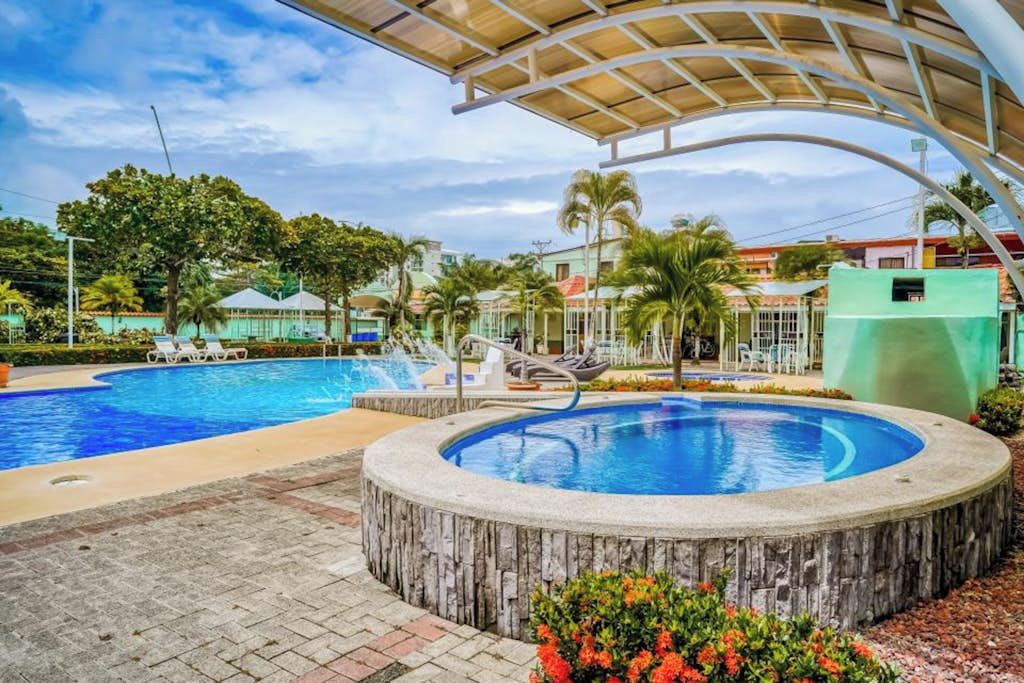 A swimming pool with a circular hot tub, lounge chairs, and a covered seating area.