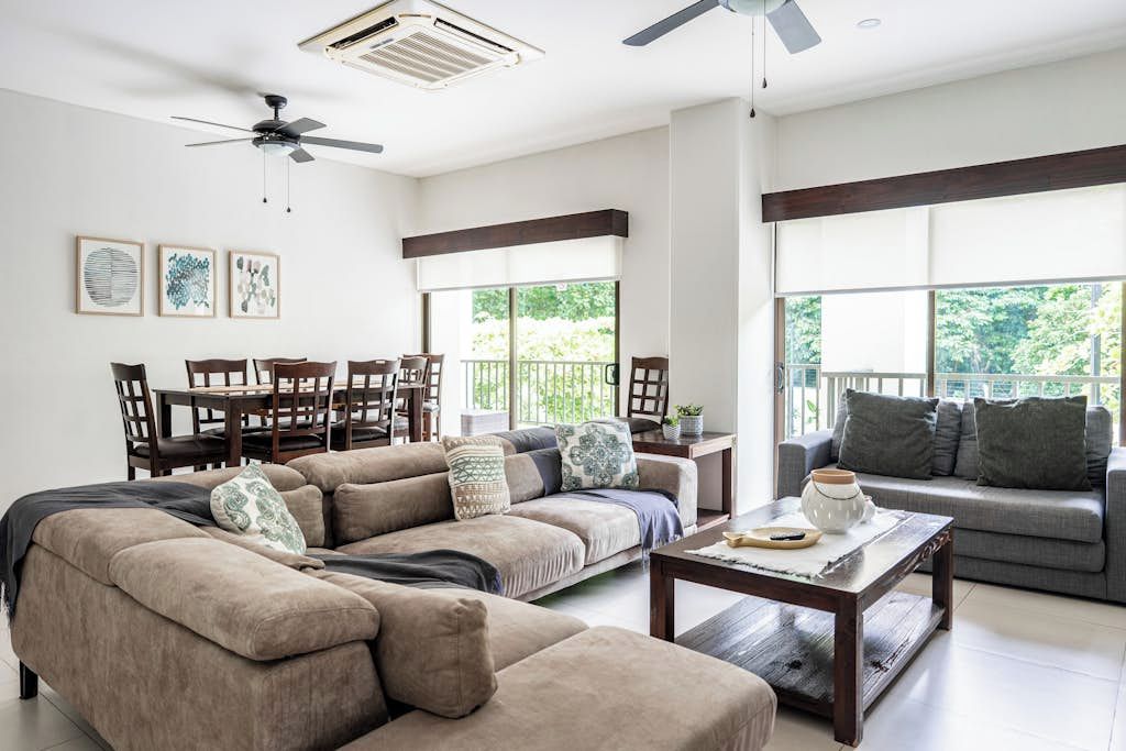 A spacious living room with a sectional sofa, a coffee table, and a dining area with chairs and a table.
