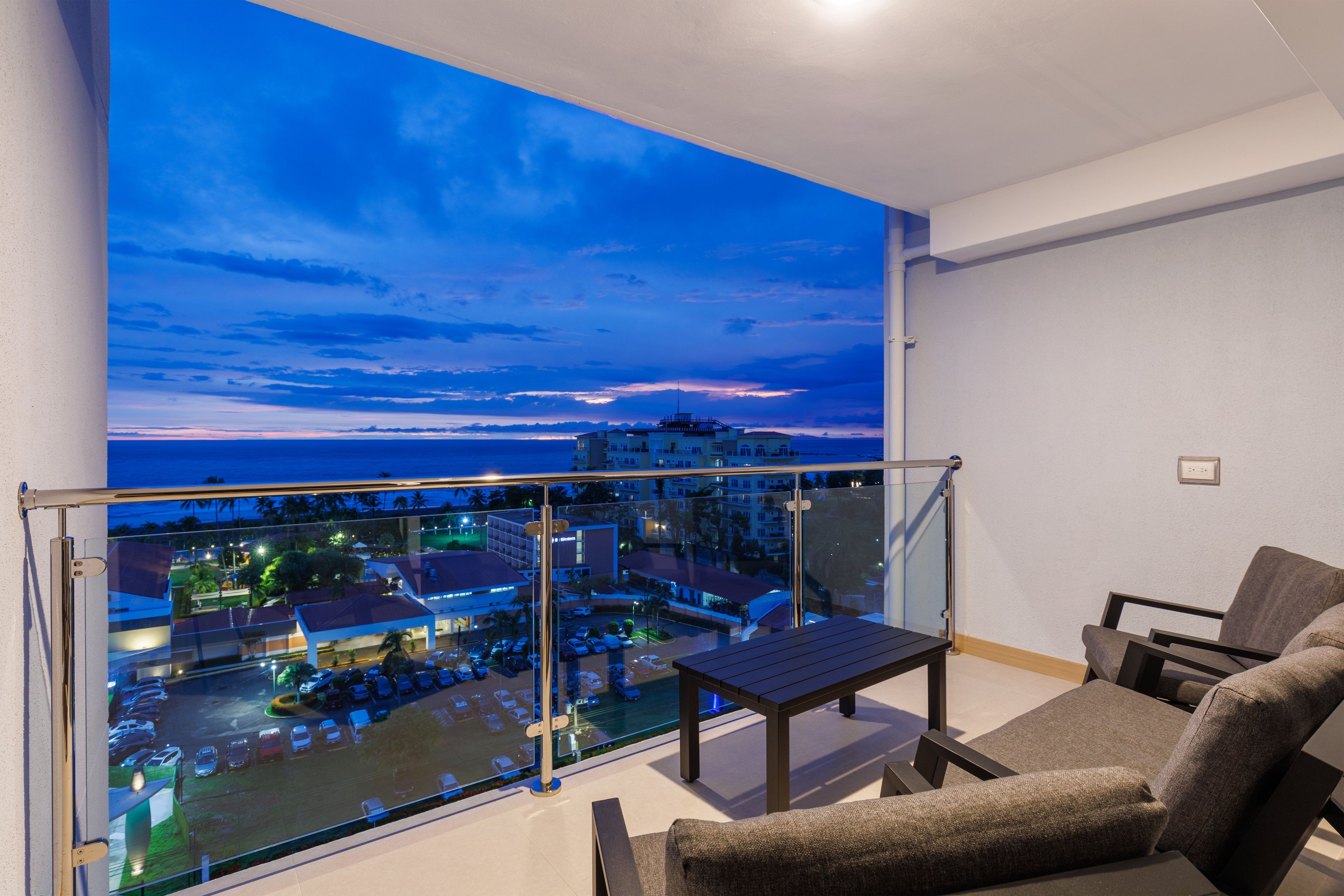 A balcony with a glass railing, a table, and two chairs.