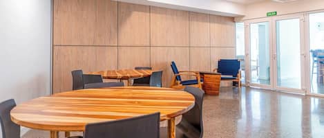 A conference room with a wooden table and chairs, a blue sofa, and a glass door labeled 'SALIDA'.