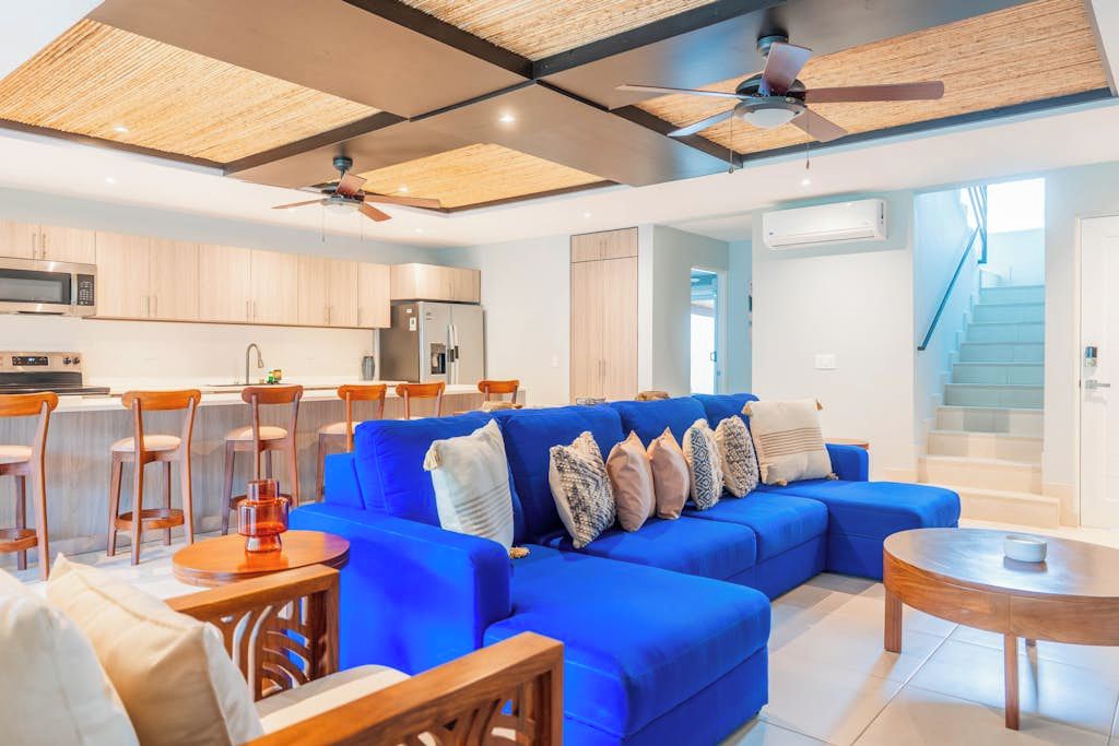 A modern living room with a blue sofa, wooden coffee table, and a ceiling fan.