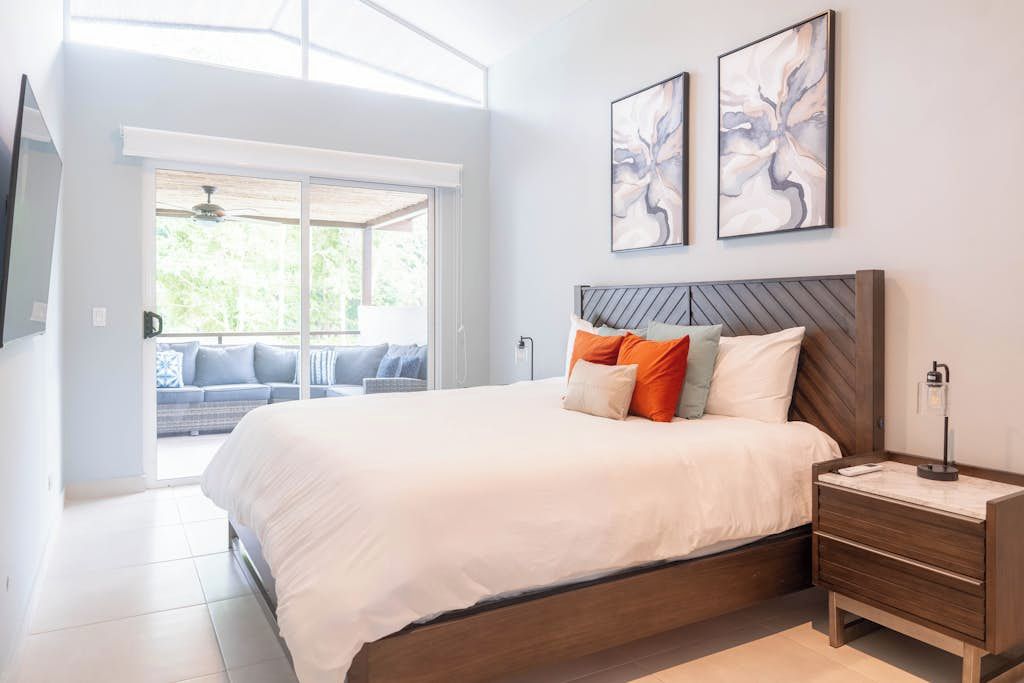 A bedroom with a large bed, a nightstand, and two wall-mounted artworks.
