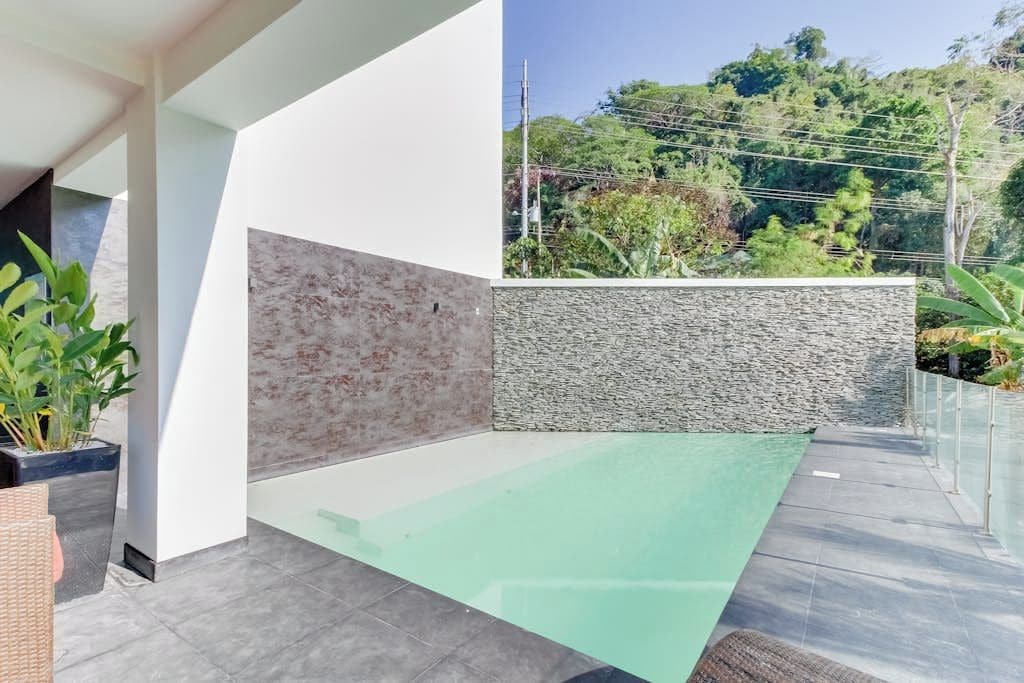 A modern outdoor space with a glass floor leading to a pool, surrounded by a white wall and a stone wall.