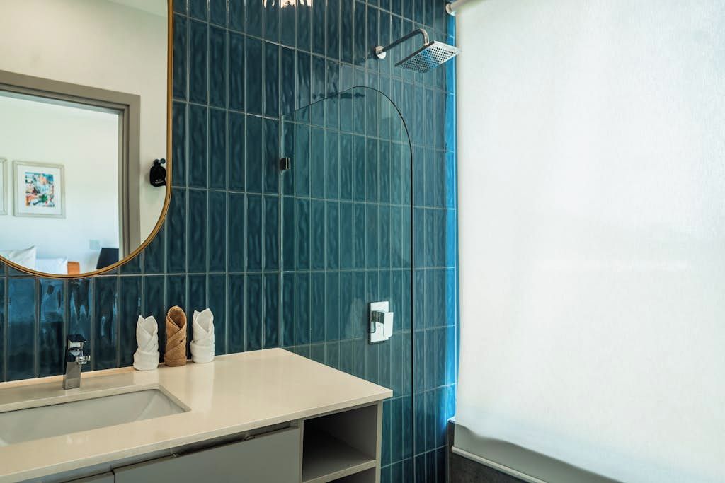Un baño con un espejo grande, un lavamanos y una zona de ducha.